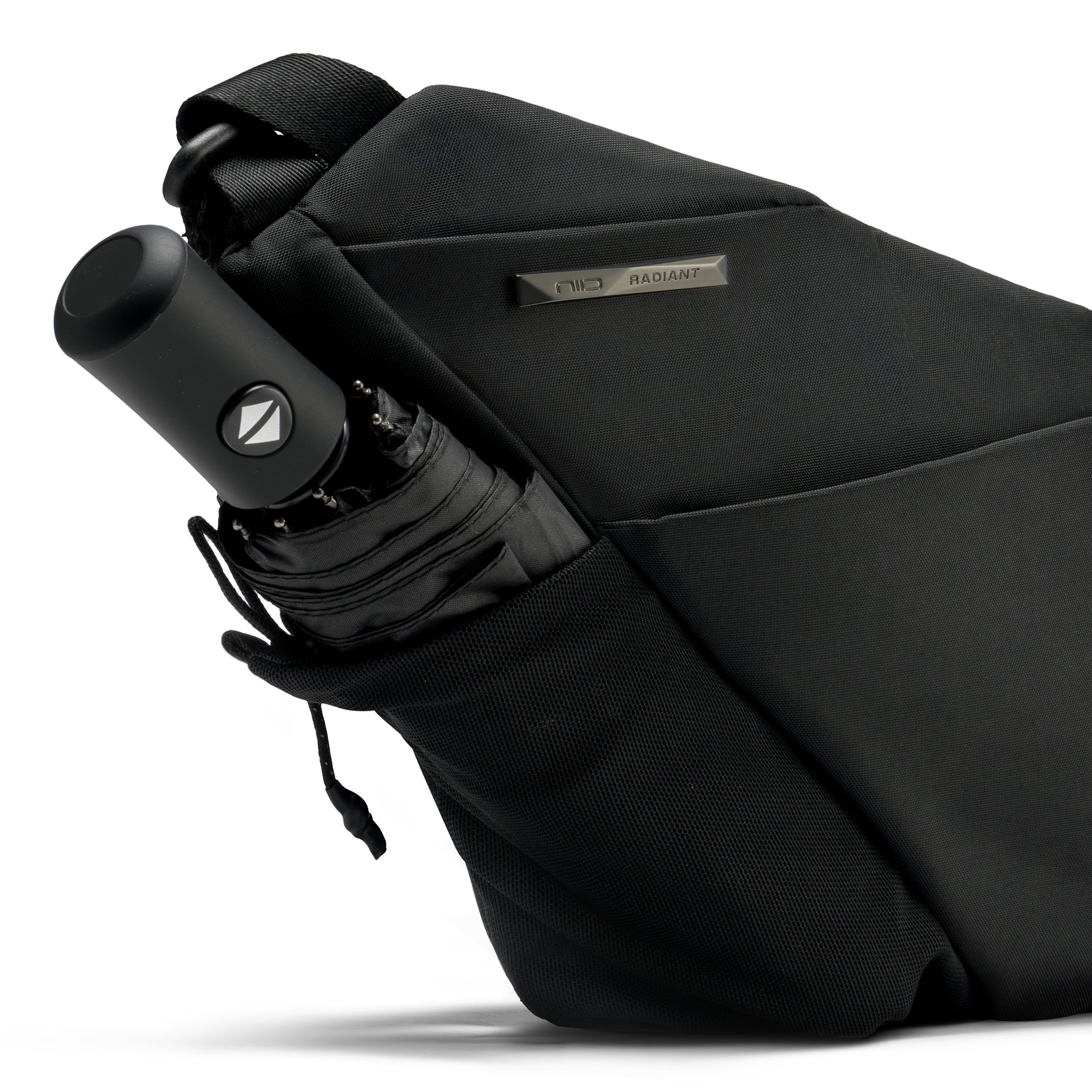 Close-up detail shot of Black Noir FINO V Ultra-slim Tech Sling crossbody bag side mesh slip pocket holding compact folding umbrella, engraved metal brand name plate on waterproof nylon exterior, showing multi-purpose outdoor storage feature on clean white studio background