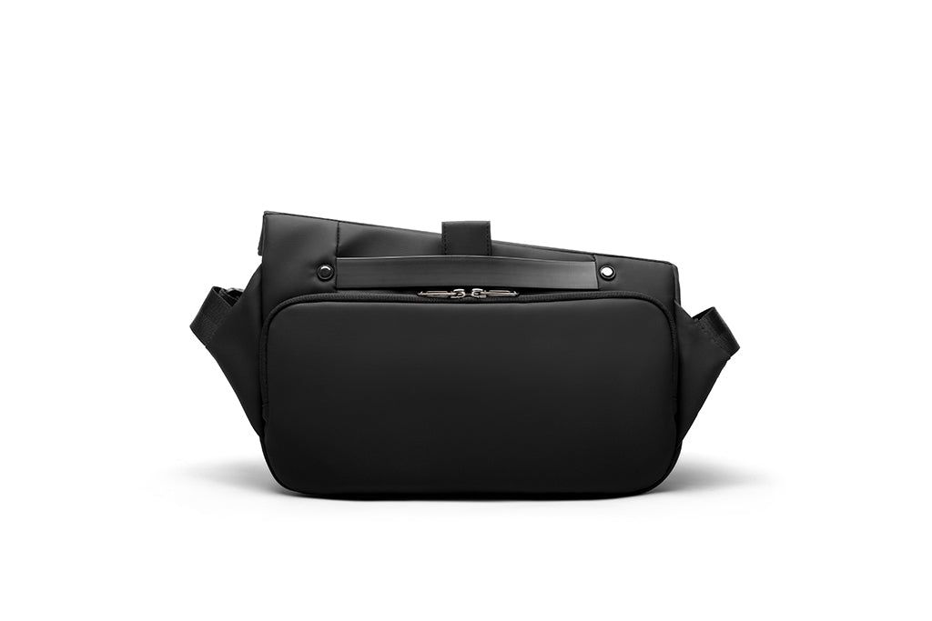 Back view of meteorite black NIID R1 Radiant Urban Sling crossbody bag, waterproof unisex nylon anti-theft chest pack with rear zipper pocket, top carry handle and adjustable shoulder straps, studio shot on plain white background for travel and daily carry