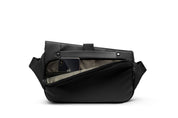 Open interior shot of meteorite black NIID R1 Radiant Urban Sling crossbody bag, built-in padded phone slot holding iPhone, multi-compartment storage design with smooth zipper and soft inner lining, waterproof nylon unisex chest pack on white background showing daily gadget storage space