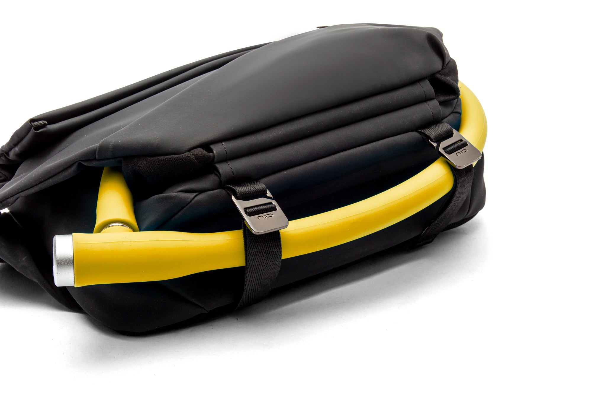 Close-up detail of meteorite black NIID R1 Radiant Urban Sling crossbody bag, bright yellow ergonomic padded shoulder strap with branded metal adjuster buckles, soft cushioned carrying design for long-time daily commute and outdoor travel, shot on clean white background