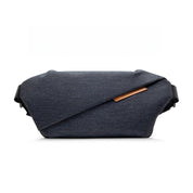 Front studio shot of Indigo NIID RO Plus Sling Bag, dark denim textured waterproof nylon crossbody chest fanny pack with diagonal fold design and genuine leather brand tag, adjustable full shoulder straps, clean 1:1 square white e-commerce product background for variant gallery