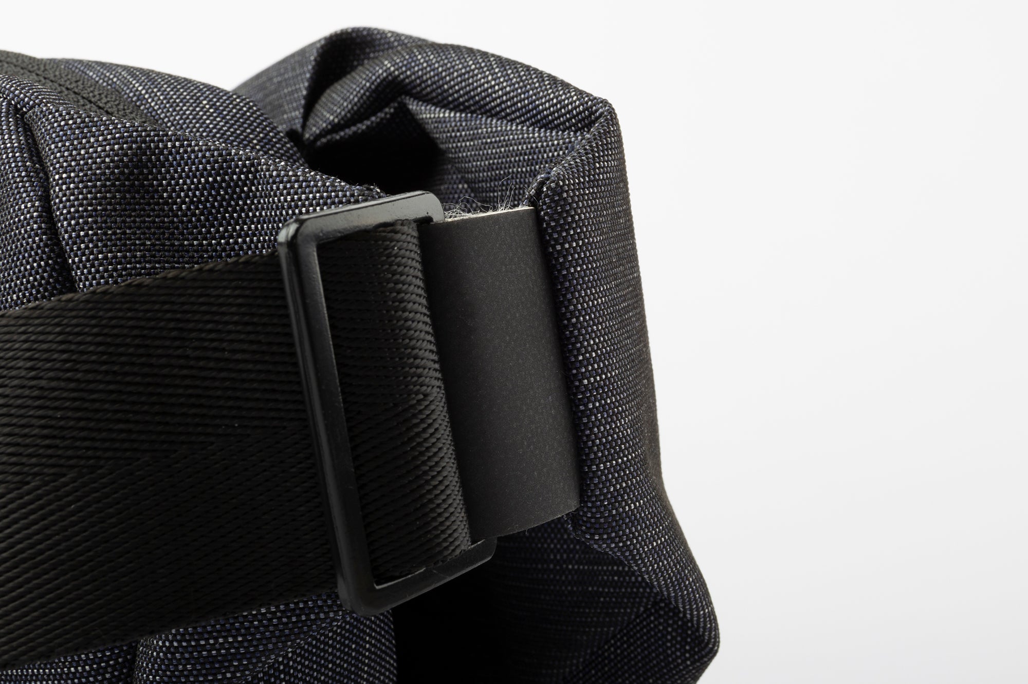 Close-up detail of black adjustable strap buckle on indigo woven NIID RO crossbody bag, thick woven shoulder strap, isolated on clean white background