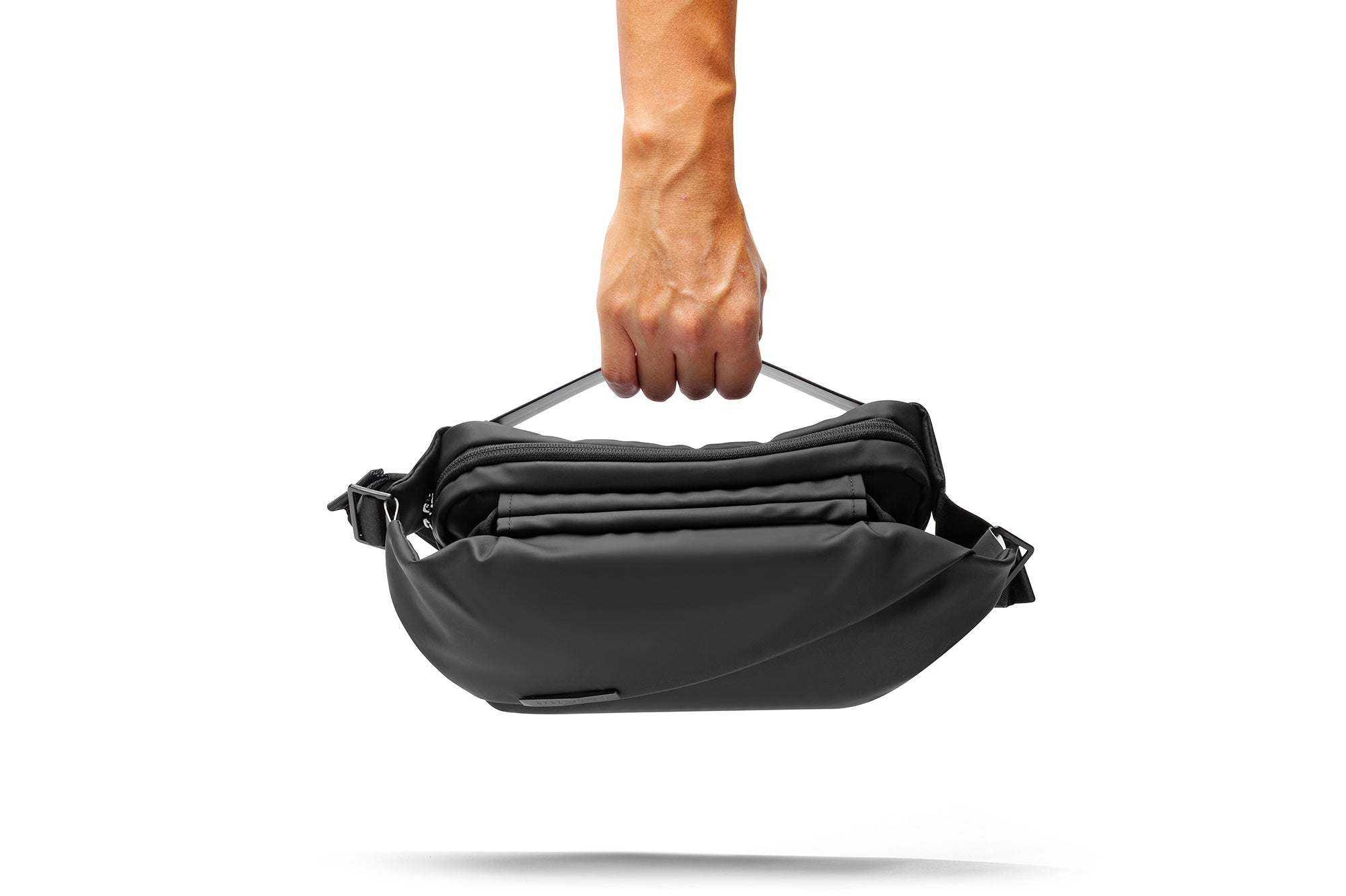 A hand holding black NIID RO Radiant crossbody chest bag with open multi-layer zipper compartments, isolated on clean white background