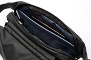 Close-up view of black NIID RO Radiant sling bag inner compartment, large padded slot holding smartphone, smooth dark blue lining and durable zipper