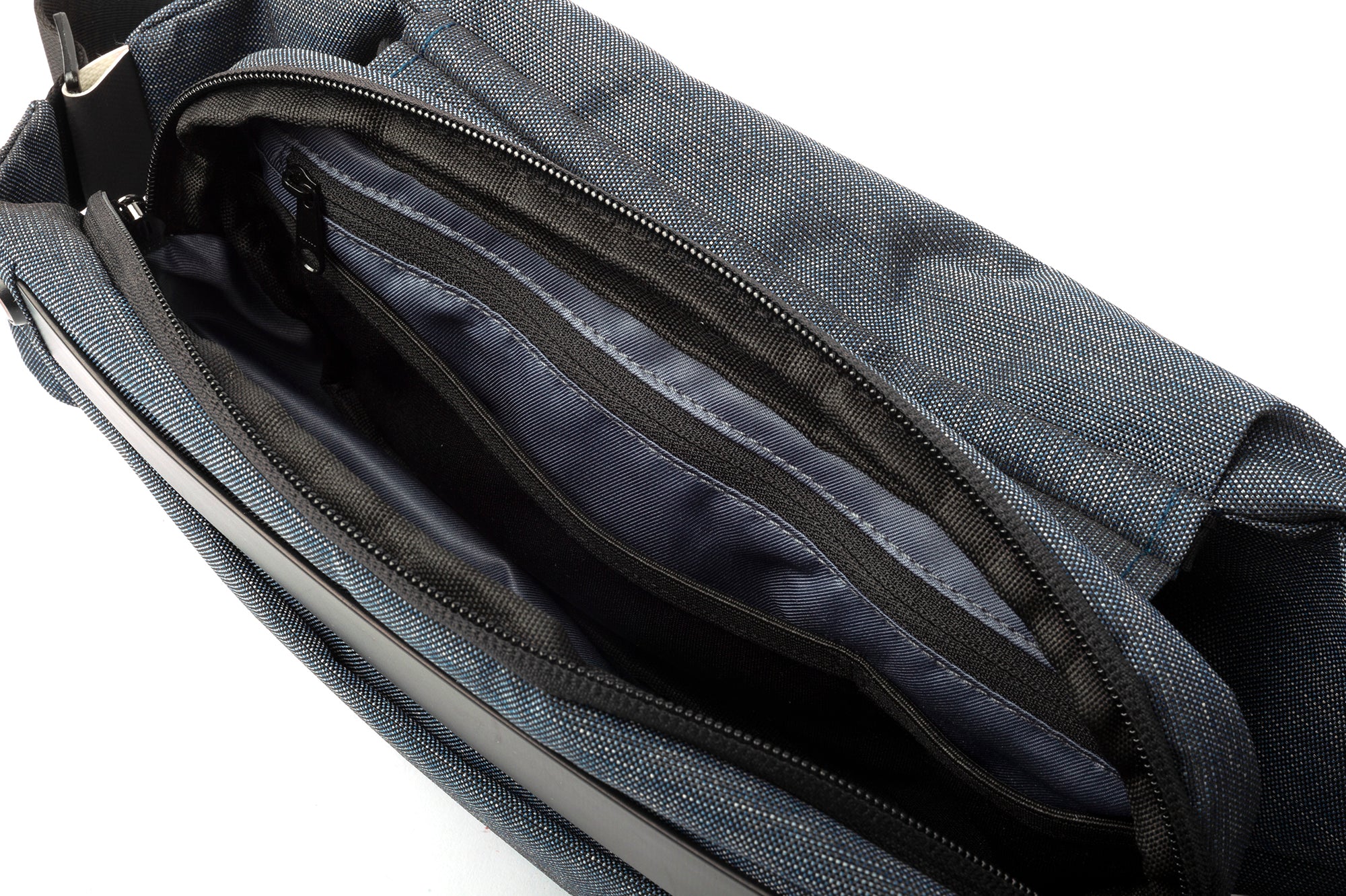 Close-up shot of open Indigo NIID RO Radiant crossbody bag interior, showing multiple layered zipper pockets and smooth dark lining, spacious organized storage compartments