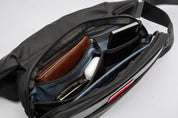 Close-up shot of open black NIID RO Radiant crossbody bag interior, multi-compartment organizer holding wallet, card holder and earbuds, demonstrating classified storage space