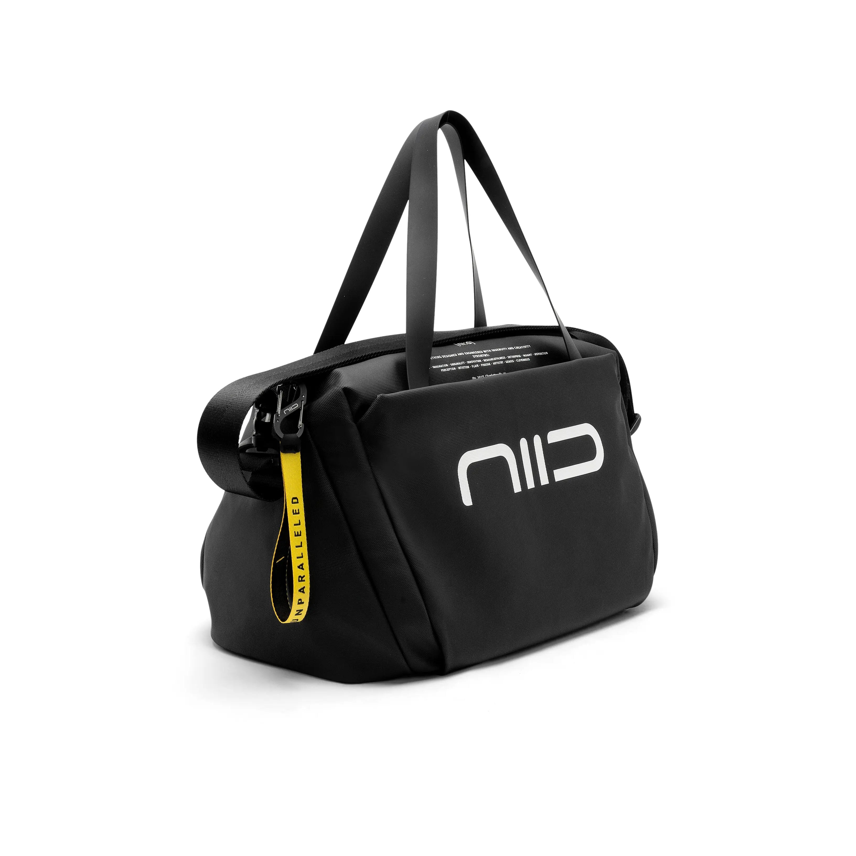 4 side view of black NIID S6 Hybrid Sling duffle crossbody bag with white NIID logo, top hand straps, detachable shoulder strap and yellow UNPARALLELED zipper pull tag, clean white studio background