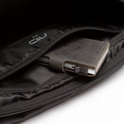 Close-up interior shot of black NIID S6 Hybrid Sling crossbody bag, zipper pocket storing leather wallet with smartphone, white NIID logo lining, clean white background