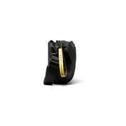 Side close-up detail shot of black NIID S6 Hybrid Sling crossbody bag, highlight bright yellow fabric tag printed with "UNPARALLELED", adjustable black shoulder strap, clean white studio background