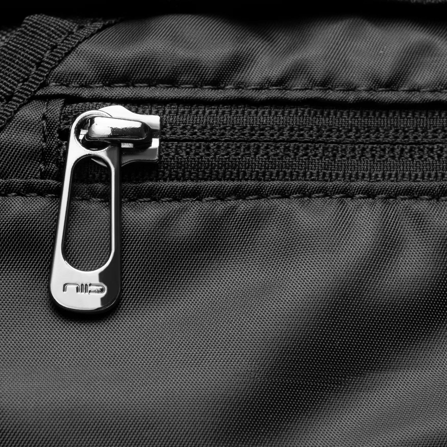 Extreme close-up detail of silver metal brand engraved zipper pull on black textured NIID S6 Hybrid Sling crossbody bag, showcasing fine fabric weave and neat stitching