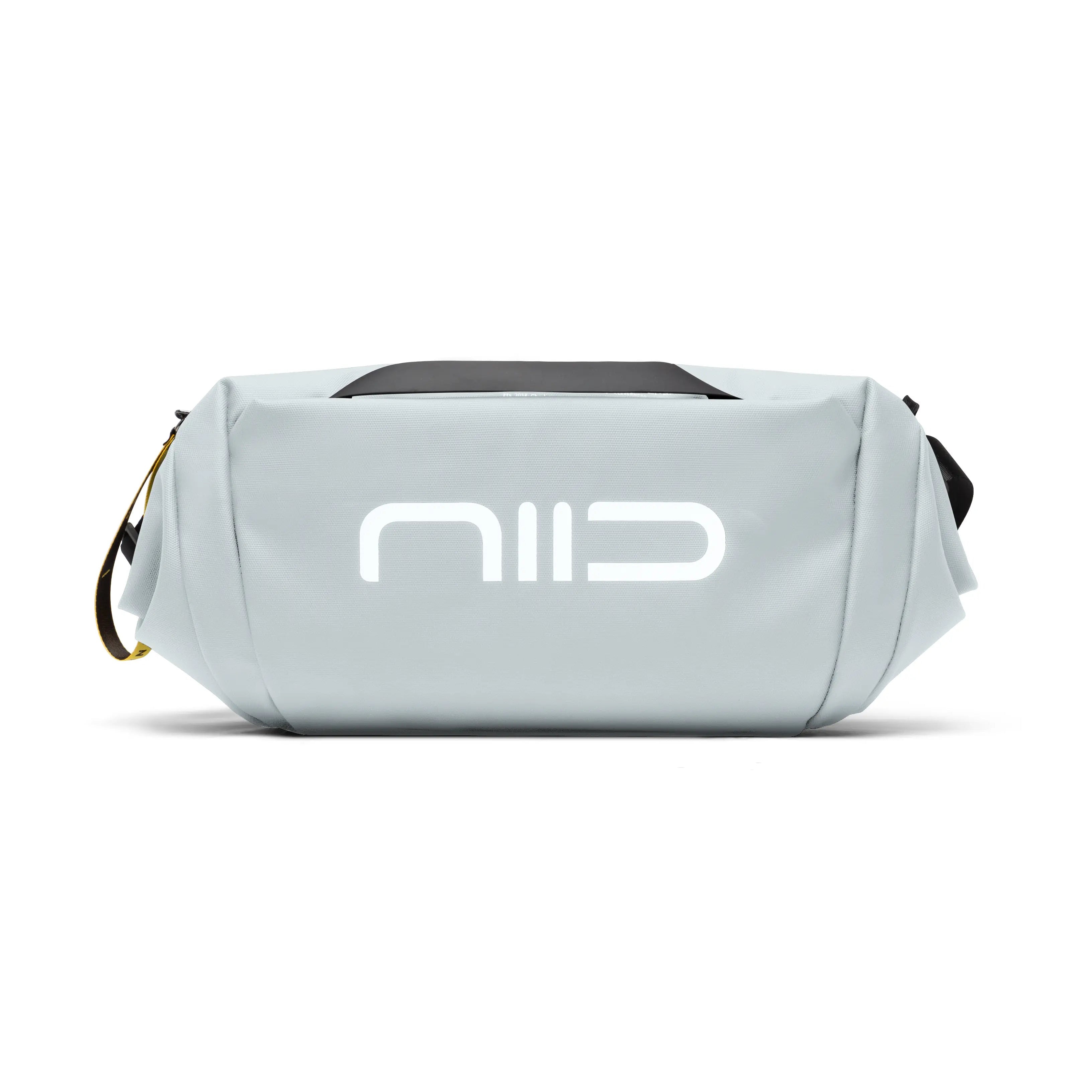 Side close-up shot of gray NIID S6 Hybrid Sling crossbody bag with large white front logo, black top handle and yellow branded zipper tag, minimalist compact sling bag on plain white background