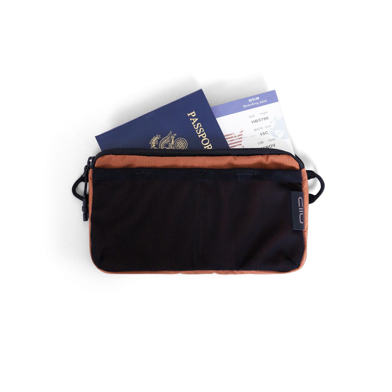 NIID NEO Element Pouch in black with Venetian Red lining, top-down shot holding passport and boarding pass, travel document organizer