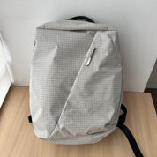 Studio indoor product shot of NIID NEO Nomad 19L Backpack‑N3 glacier gray grid fabric, placed on light wooden table against white wall, clean front view showing minimalist silhouette.