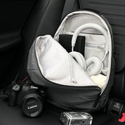 Car interior lifestyle shot of open NIID NEO Nomad 19L Backpack‑N3 mineral gray, displays inner compartment layout, packed with headphones, camera gear, showing ample storage space for travel and photography essentials.