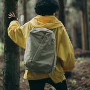 Back view of model wearing NIID NEO Nomad 19L Backpack‑N3 sage green in forest, lightweight water‑resistant daypack for hiking, casual outdoor adventure and weekend short travel.