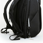 Close-up of NIID NEO Nomad Backpack N4 side pocket with NIID branded key leash and key tether, showing back panel mesh padding.