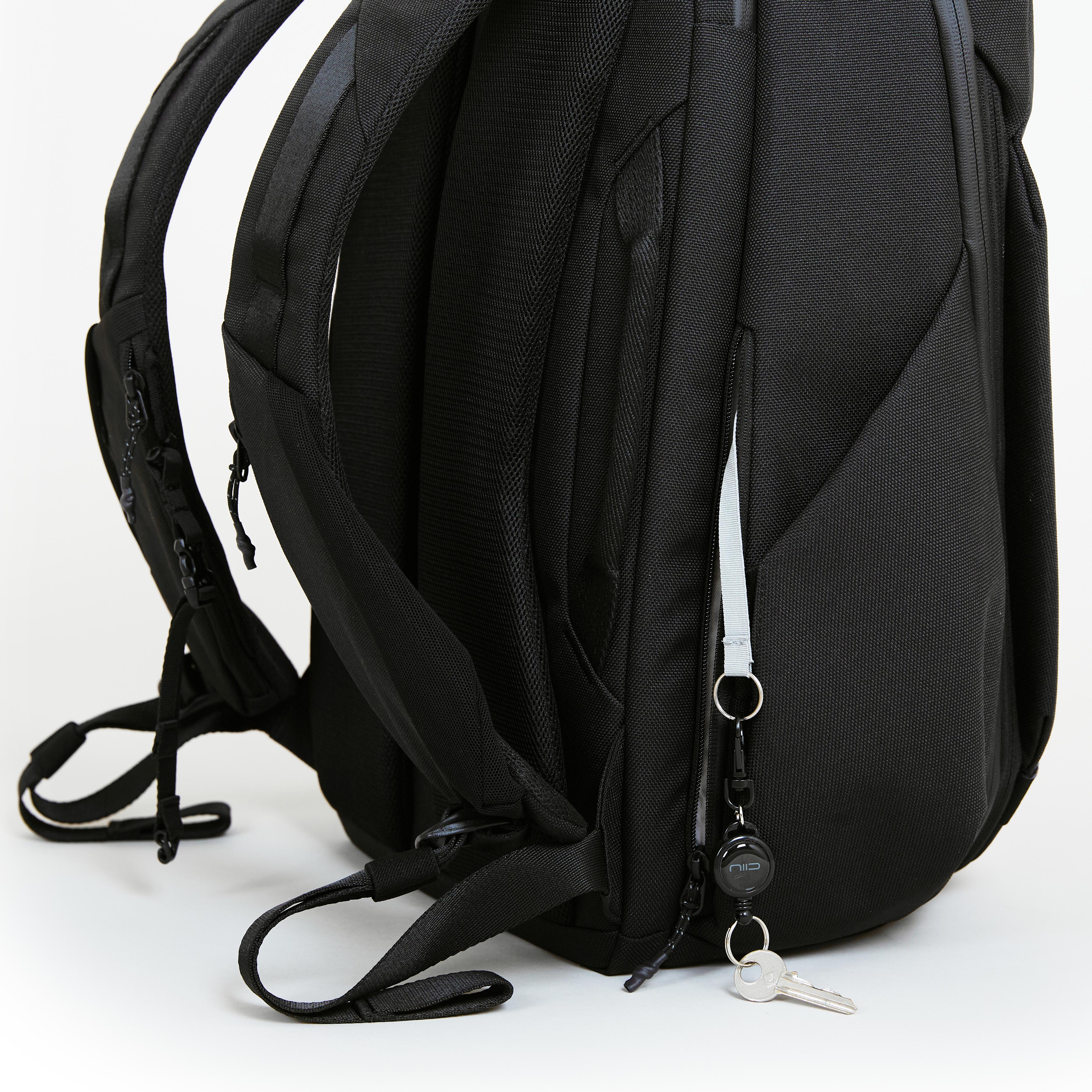 Close-up of NIID NEO Nomad Backpack N4 side pocket with NIID branded key leash and key tether, showing back panel mesh padding.