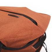 Close-up of NIID NEO Nomad Backpack N4 in Venetian Red, diagonal zipper and NIID metal logo plate on textured fabric.
