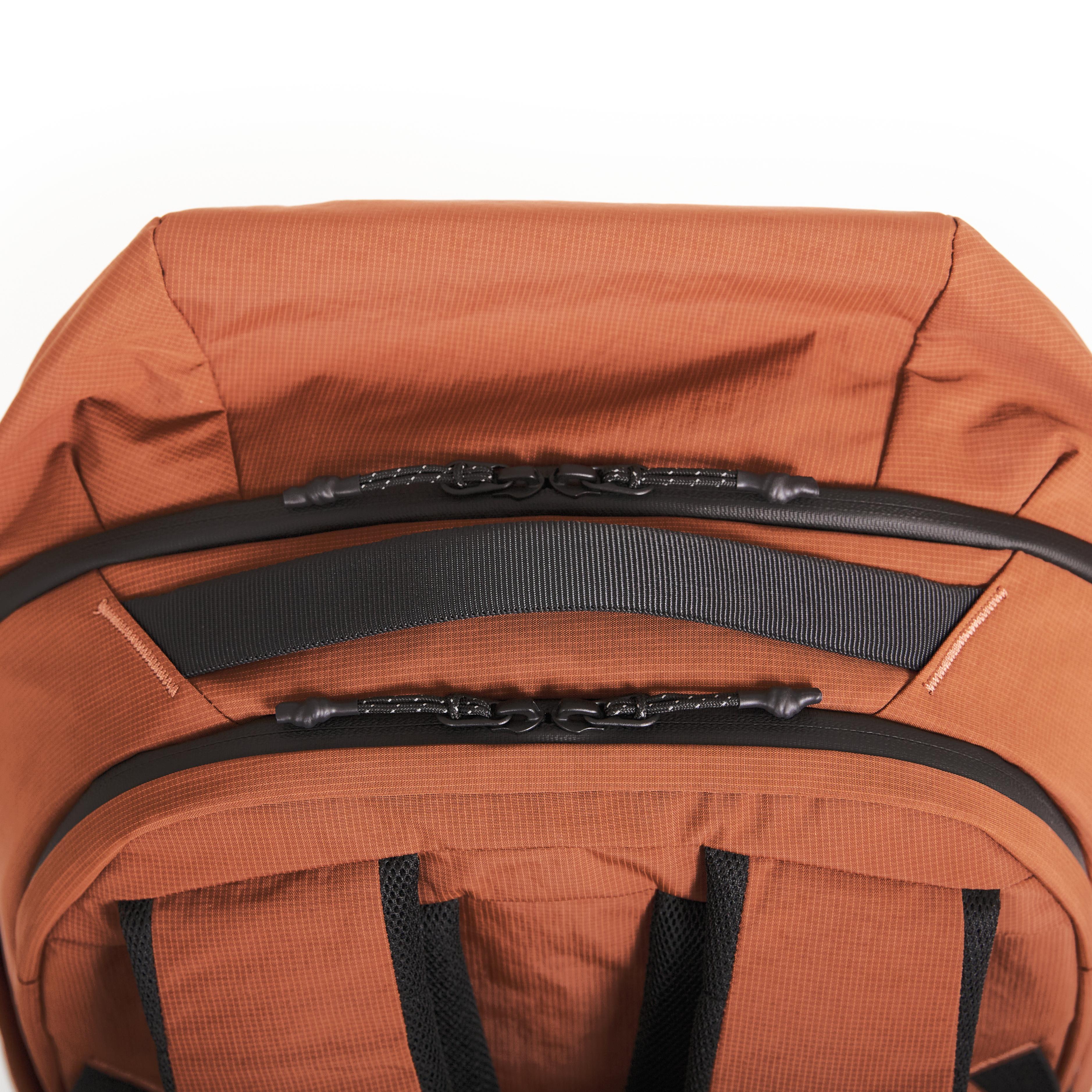 Close-up of NIID NEO Nomad Backpack N4 in Venetian Red top carry handle and dual zipper pulls, back panel mesh visible.