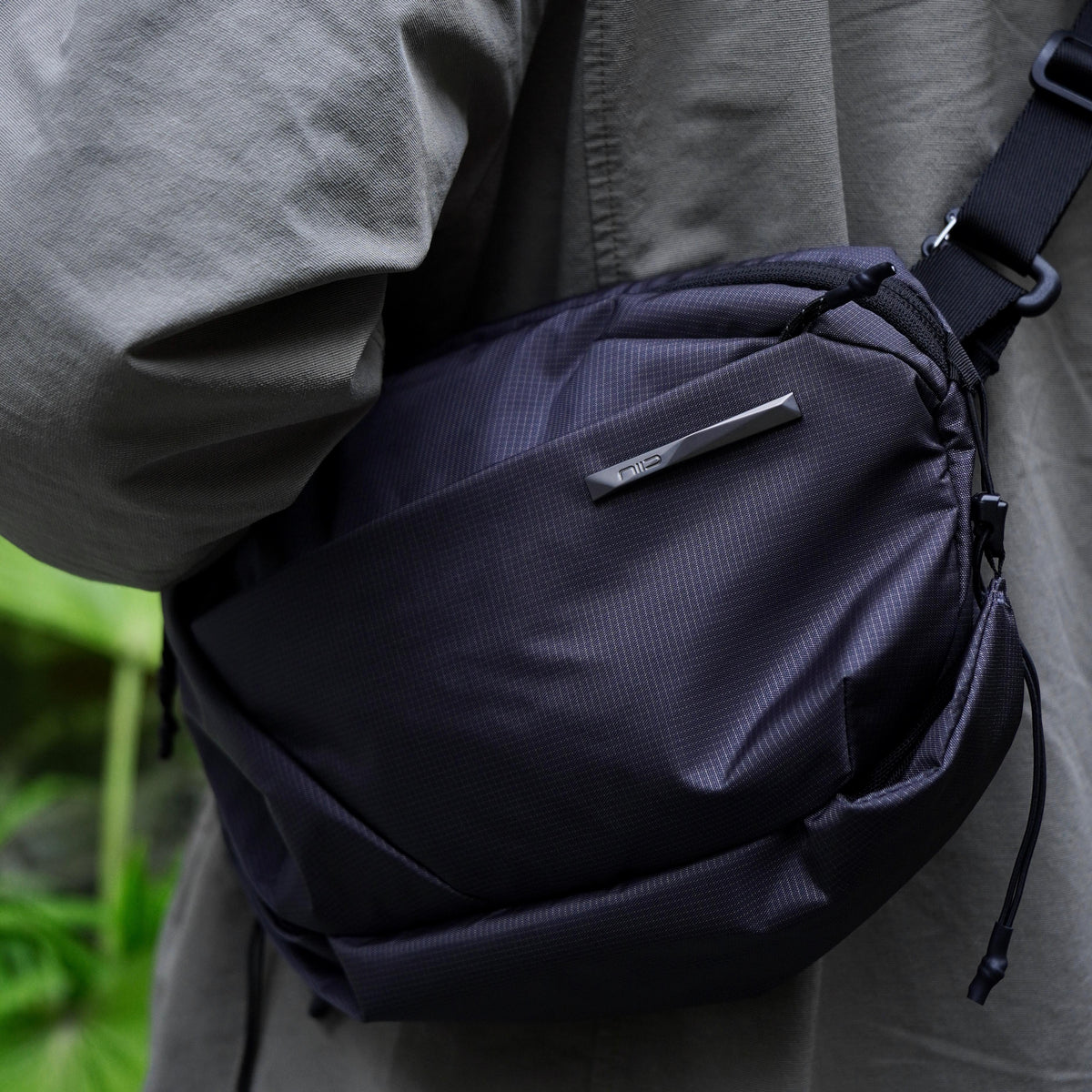 NIID NEO Nomad 4L Sling Bag‑N1 graphite gray diamond grid sling bag close‑up worn on waist, textured fabric and NIID logo detail, matched with casual jacket, outdoor EDC crossbody bag