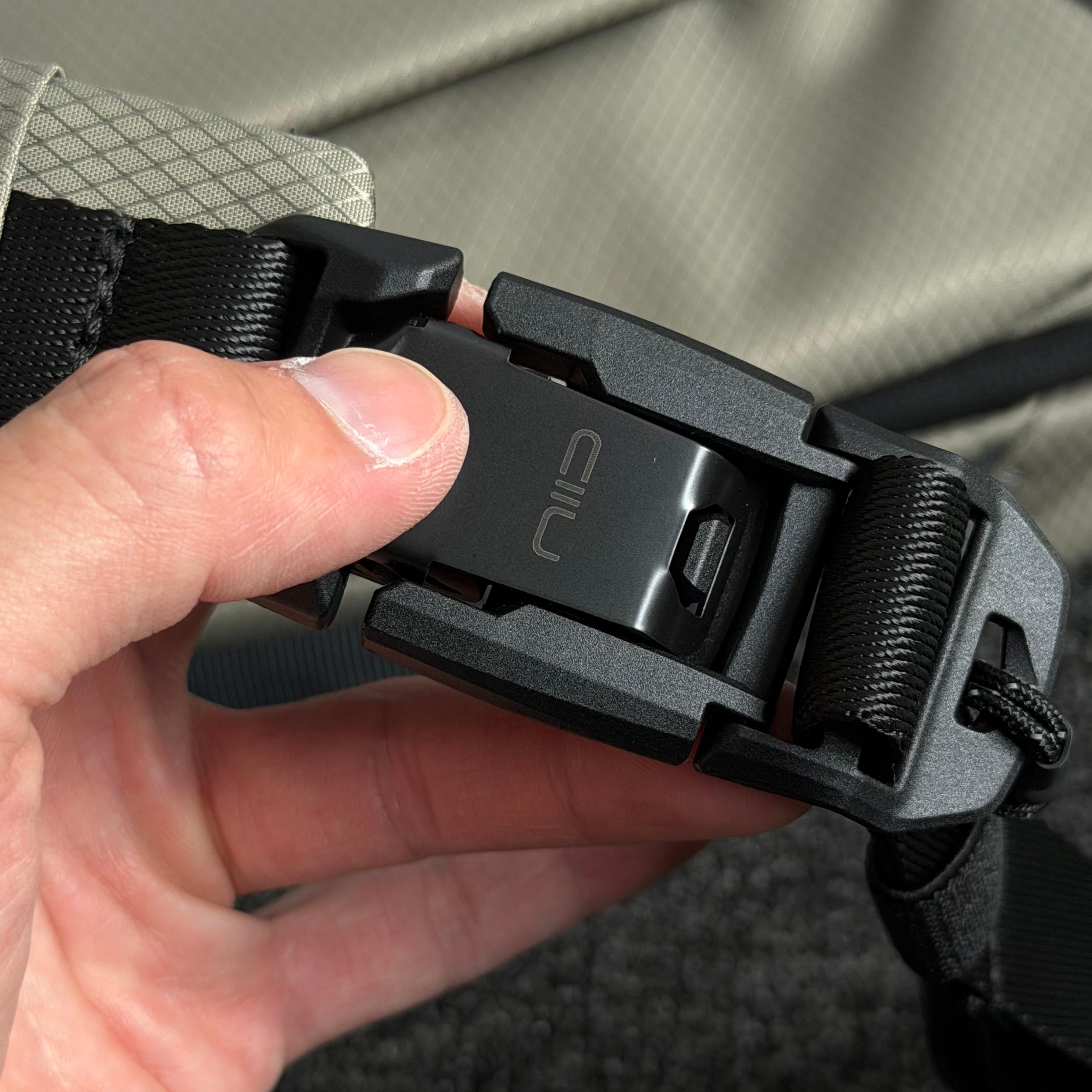 Close‑up shot of NIID NEO Nomad 5L Sling Bag‑N1L black quick‑release magnetic buckle engraved with NIID logo, hand demonstrating fast snap function, durable hardware detail.
