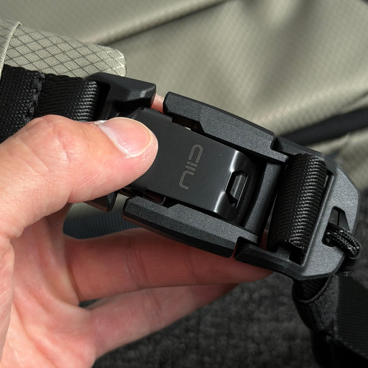 Close‑up shot of NIID NEO Nomad 5L Sling Bag‑N1L black quick‑release magnetic buckle engraved with NIID logo, hand demonstrating fast snap function, durable hardware detail.