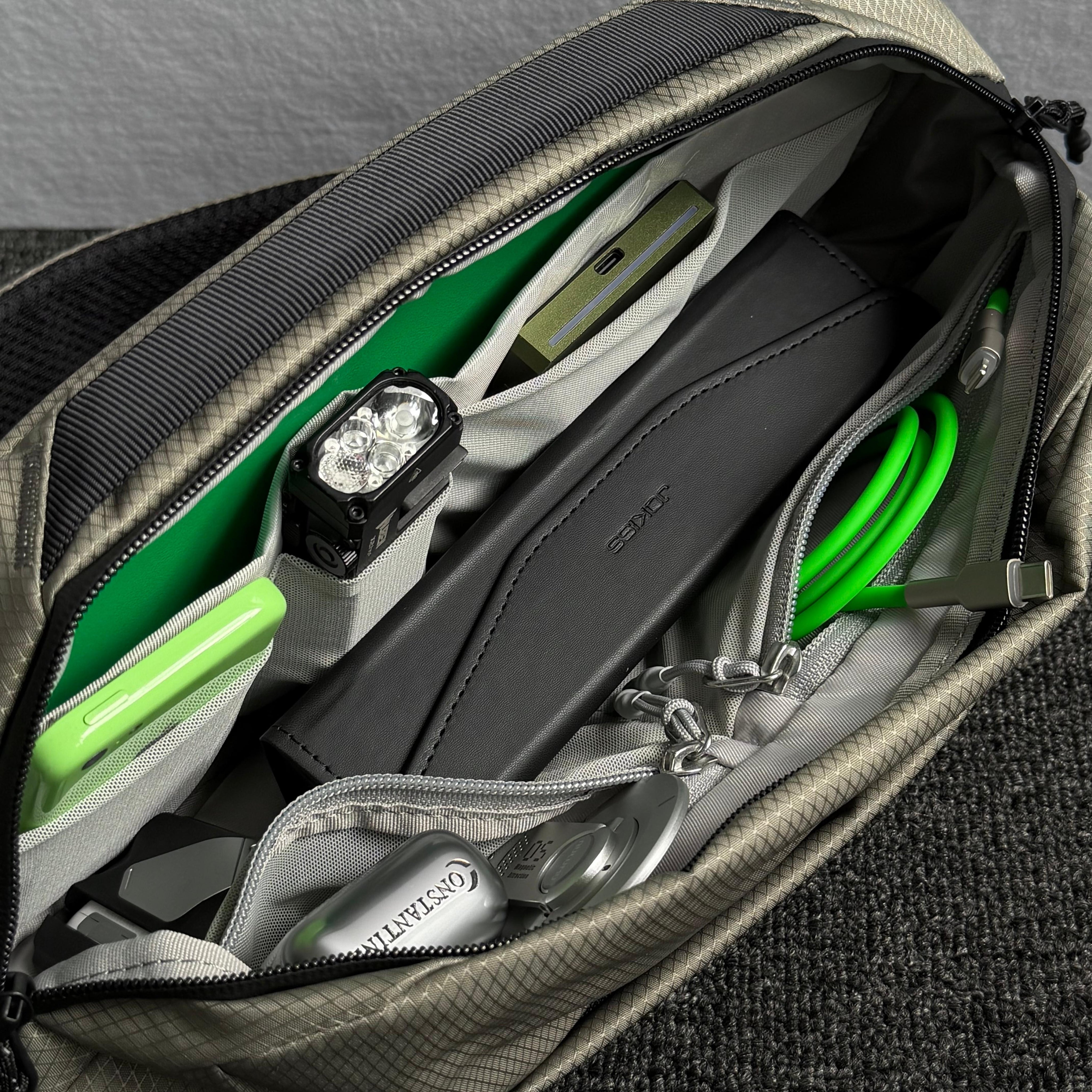 Close‑up interior shot of open NIID NEO Nomad 5L Sling Bag‑N1L pearly gray, neatly organized compartments packed with cables, power bank, earbuds and daily EDC gear, show multi‑pocket storage design.