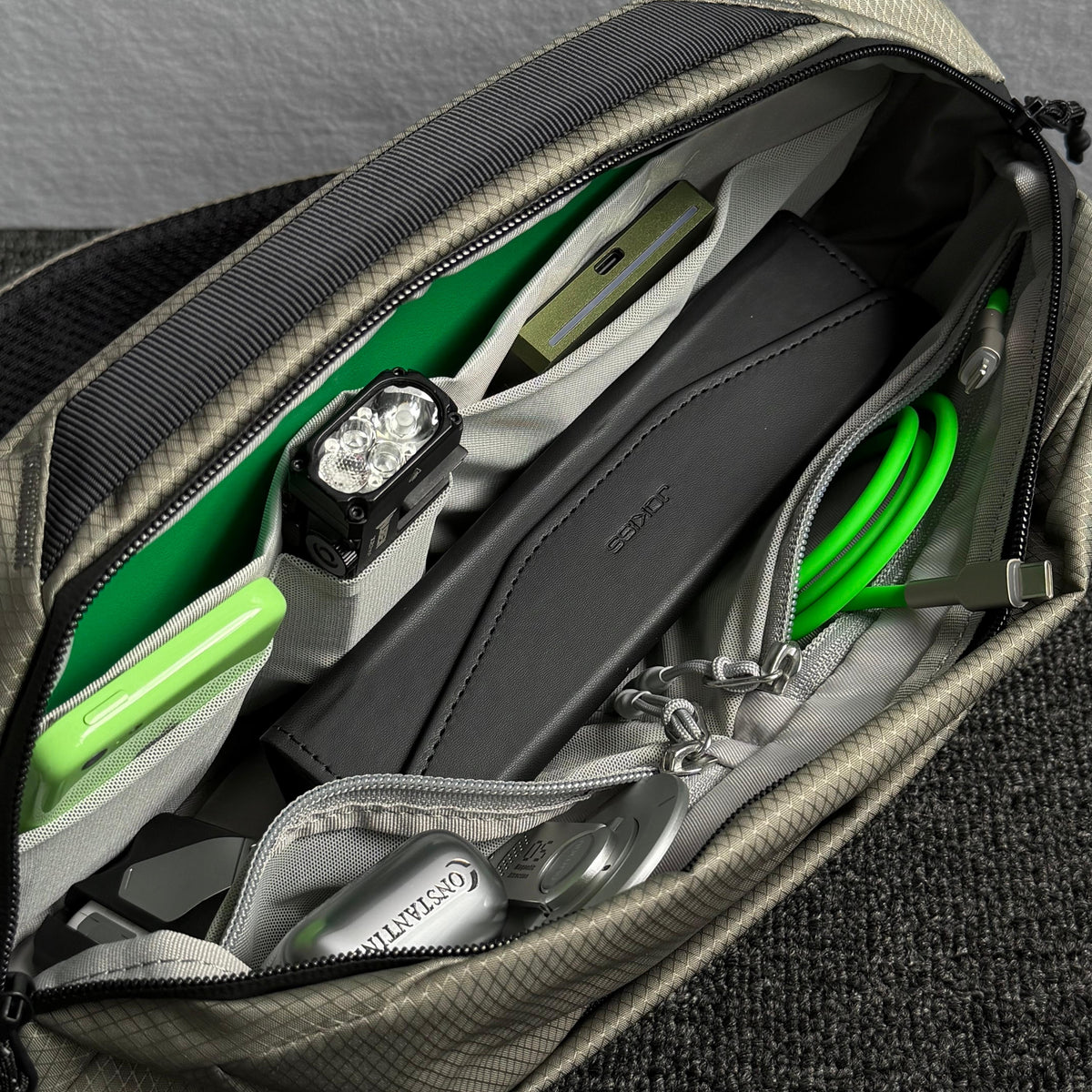 Close‑up interior shot of open NIID NEO Nomad 5L Sling Bag‑N1L pearly gray, neatly organized compartments packed with cables, power bank, earbuds and daily EDC gear, show multi‑pocket storage design.
