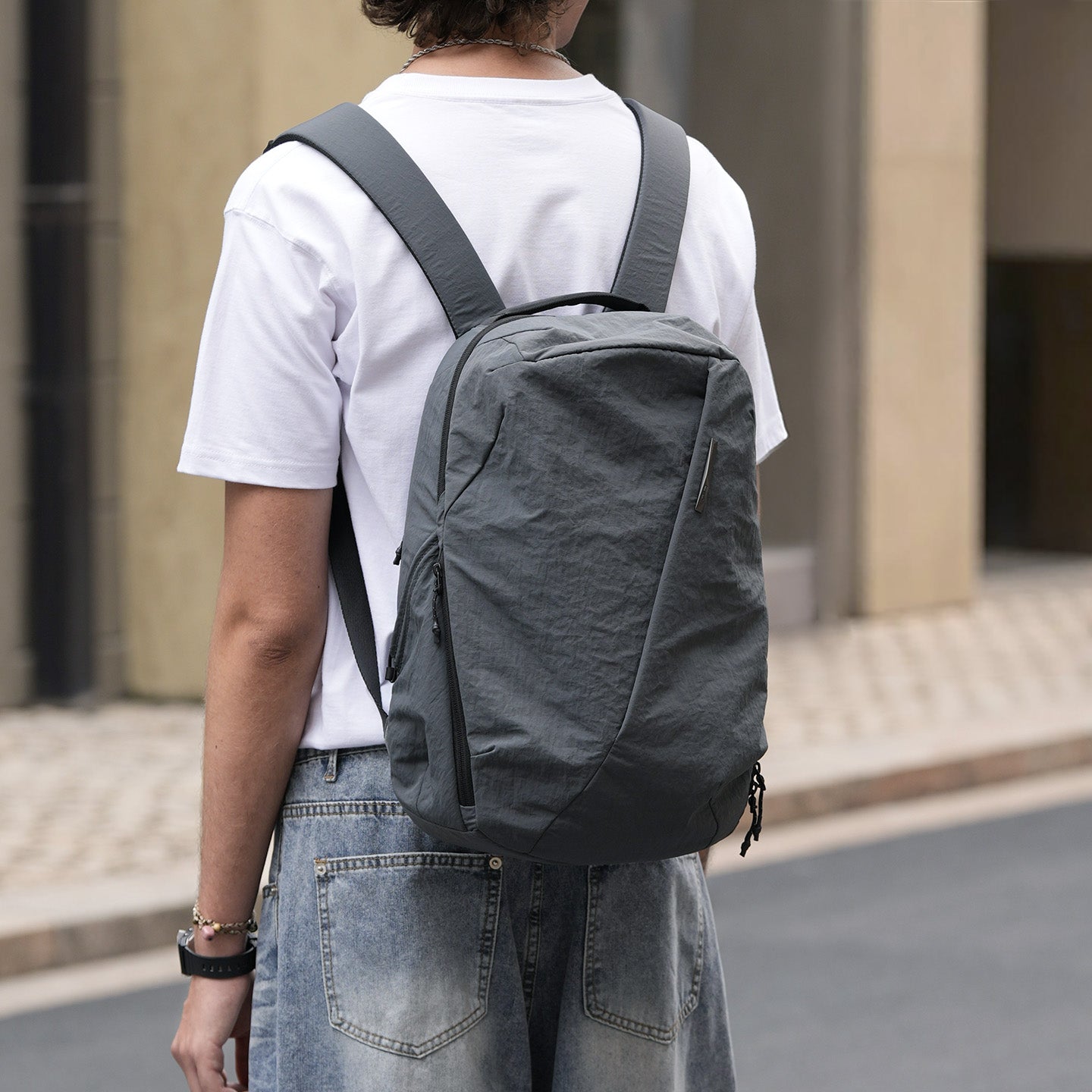 Male model wearing mineral‑grey NIID NEO Nomad Backpack‑N3 on urban street