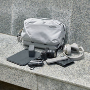 NIID N2 pearly gray sling bag with daily travel gadgets flat lay shot on stone bench