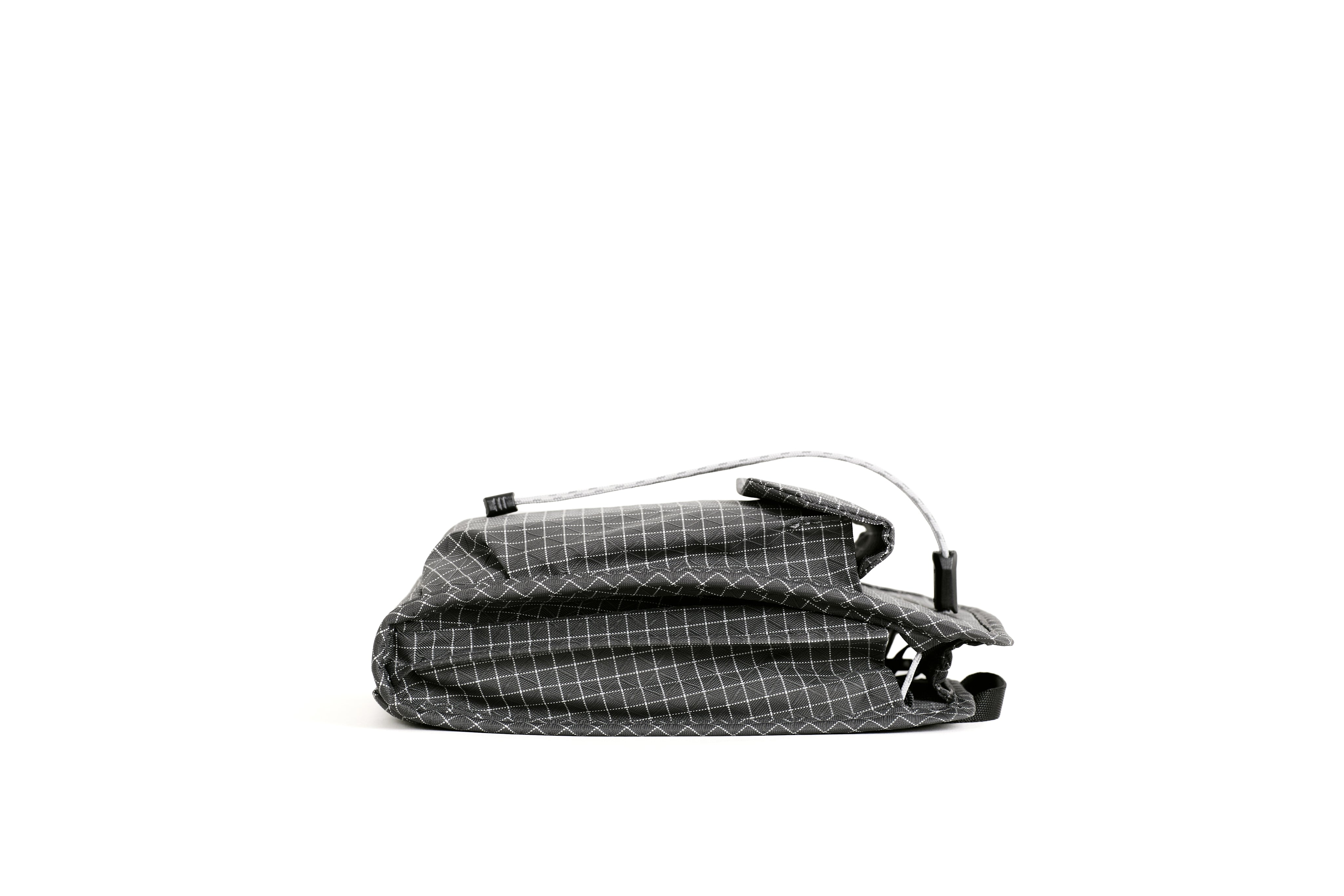 NIID NEO Nomad Pouch in Graphene Gray Ripstop, side profile flat lay showing compact folded shape and drawstring cords, white background.