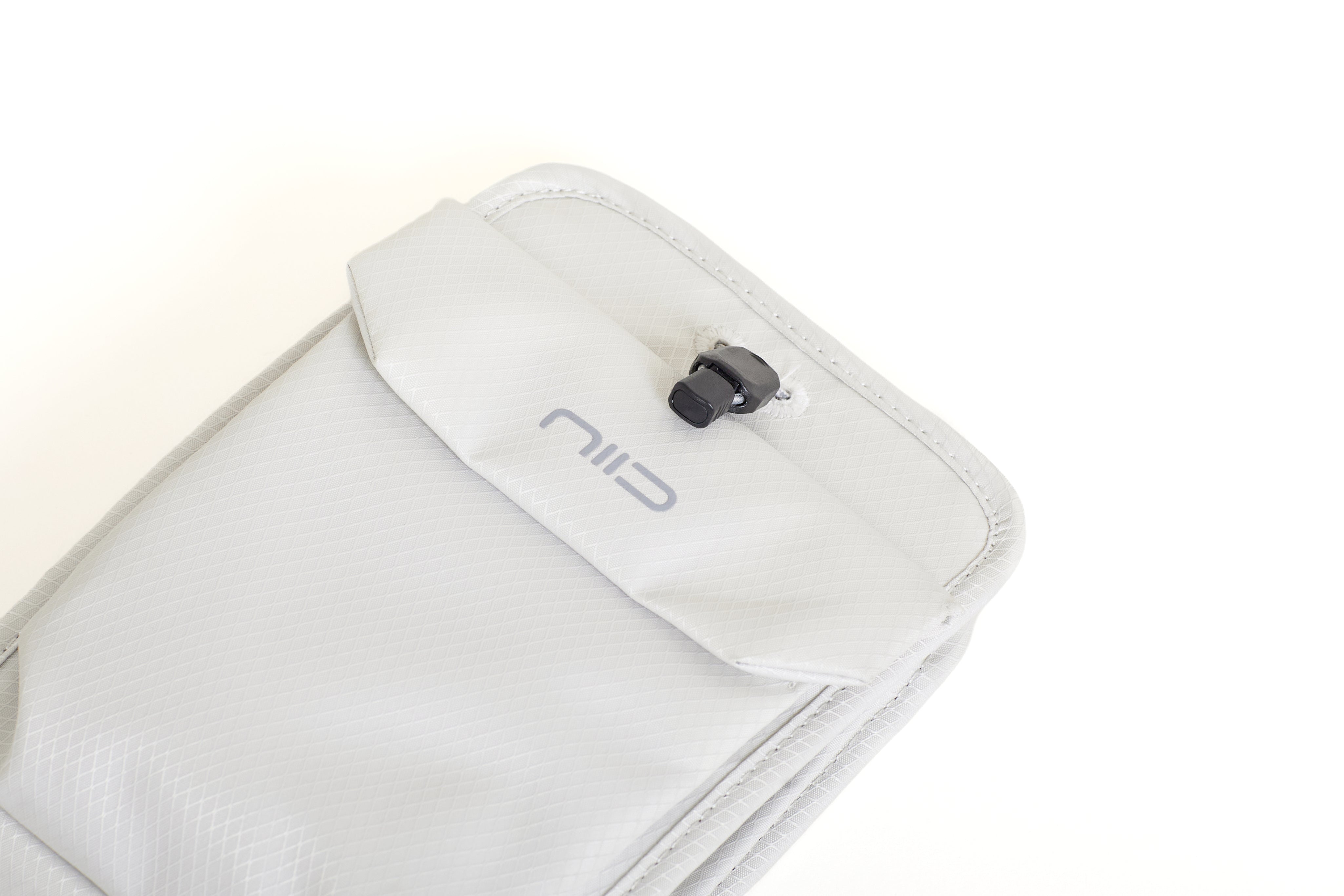 Close-up of Pearly White Nomad Pouch angled front flap showing NIID logo and black drawstring cord lock.