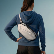 Woman back view carrying NIID NEO Nomad Sling Bag‑N1L pearly‑gray crossbody chest pack, casual outfit, solid‑color background
