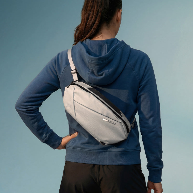 Woman back view carrying NIID NEO Nomad Sling Bag‑N1L pearly‑gray crossbody chest pack, casual outfit, solid‑color background