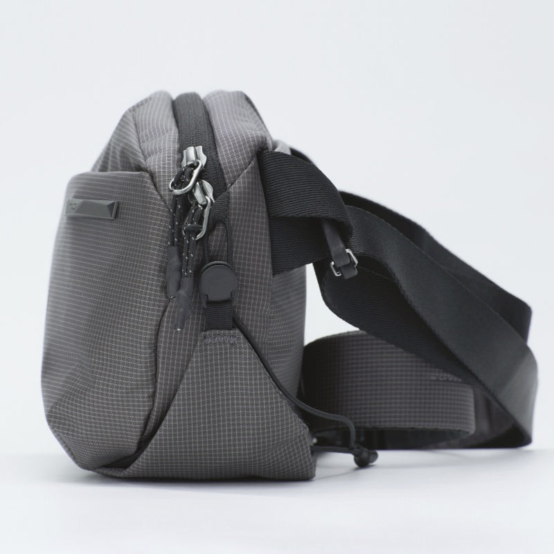 NIID NEO Nomad Sling Bag N1 Graphite Gray, grid textured waterproof crossbody chest pack, side profile shot with wide adjustable shoulder strap on plain white background