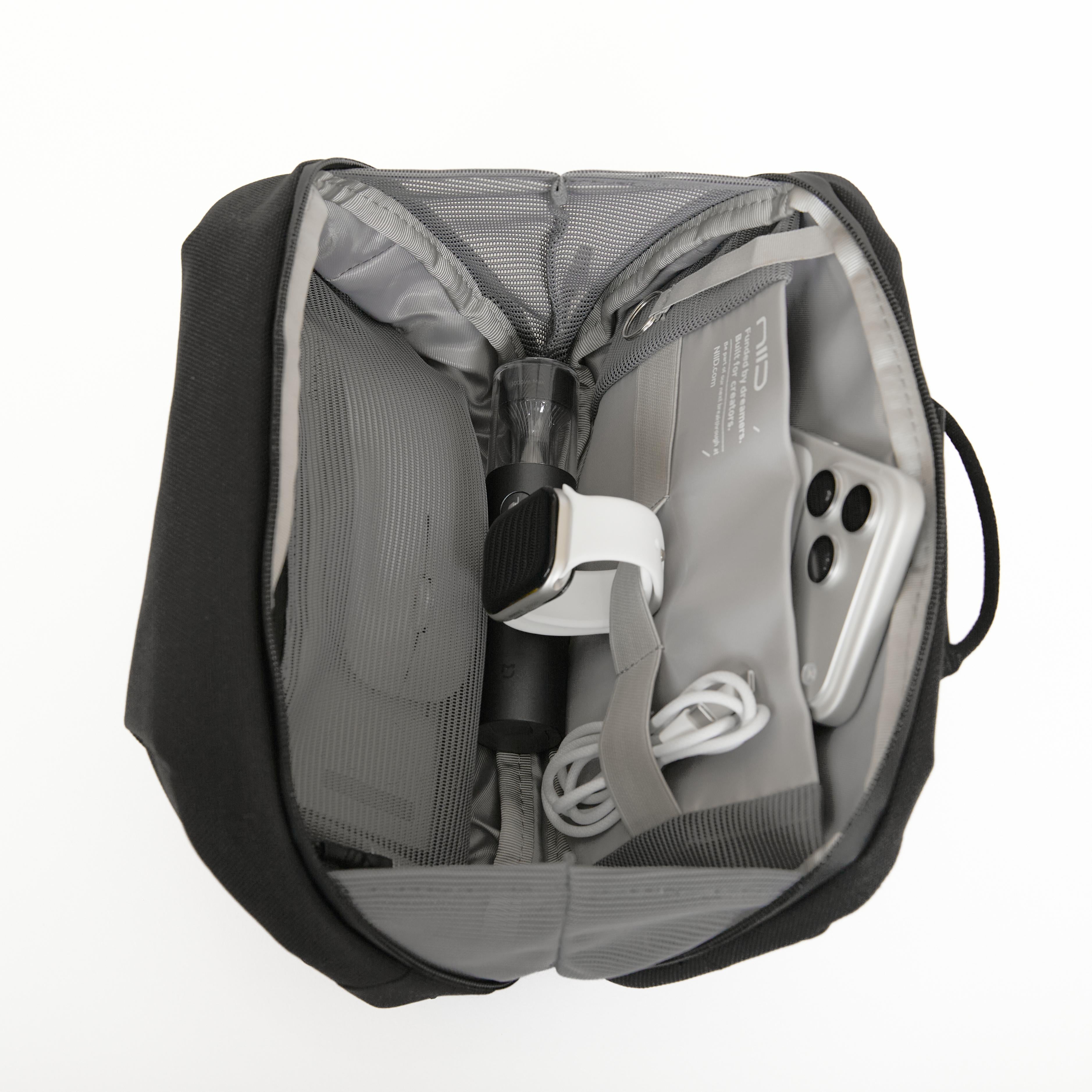 NIID NEO Tech Pouch in FortiTex Black Cordura open showing interior with smartwatch, phone, charging cable and bottle.