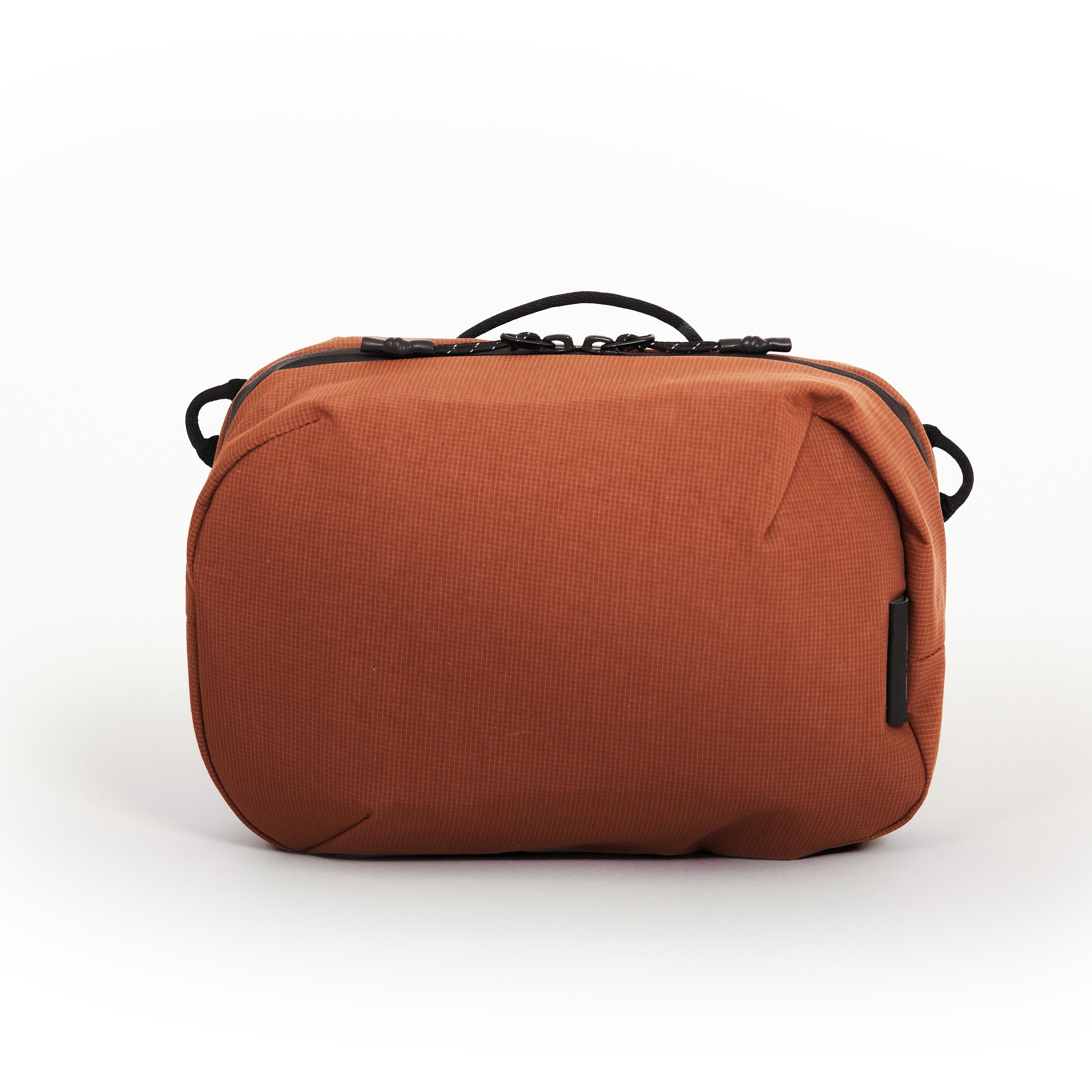 NIID NEO Tech Pouch in Venetian Red front view showing top handle, dual zipper pulls and side attachment loops.