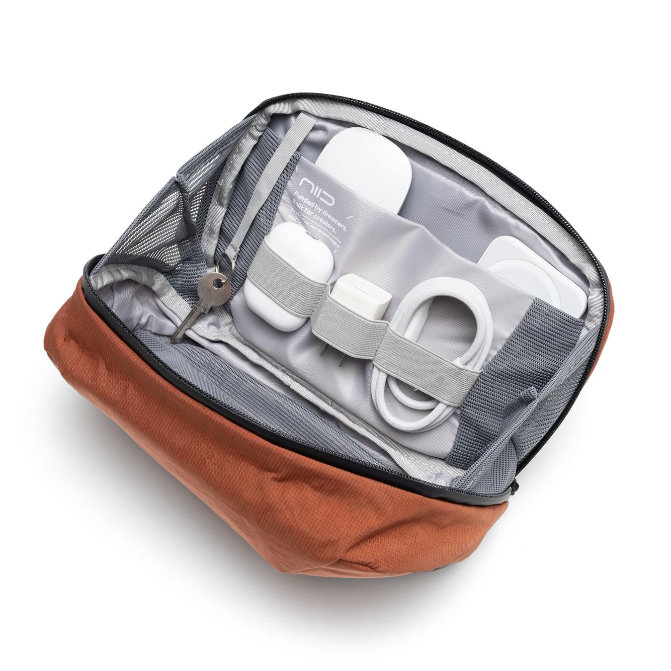NIID NEO Tech Pouch in Venetian Red open showing mesh pockets with earbuds, charger, cable and key.