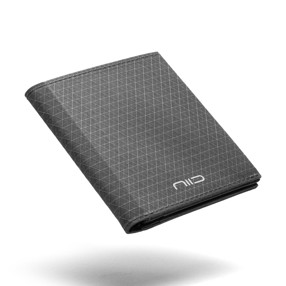 Floating angled shot of dark gray grid pattern Cordura fabric NIID NEX slim bifold wallet on clean white background, subtle triangular geometric grid texture all over surface, white embossed NIID logo on lower front, soft shadow underneath, wear-resistant outdoor men’s minimalist EDC card holder product photo
