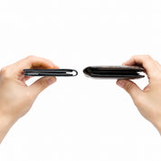Two hands holding wallets side-by-side for thickness comparison on plain white background; left hand holds ultra-thin black NIID NEX bifold wallet, right hand holds traditional thick leather wallet, visual slim profile contrast demonstration shot