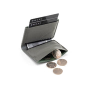 Open dark gray NIID NEX slim bifold wallet on plain white background, credit cards inserted in card slots, loose coins spilling out from built-in coin pocket, interior storage detail shot of minimalist men’s everyday carry wallet