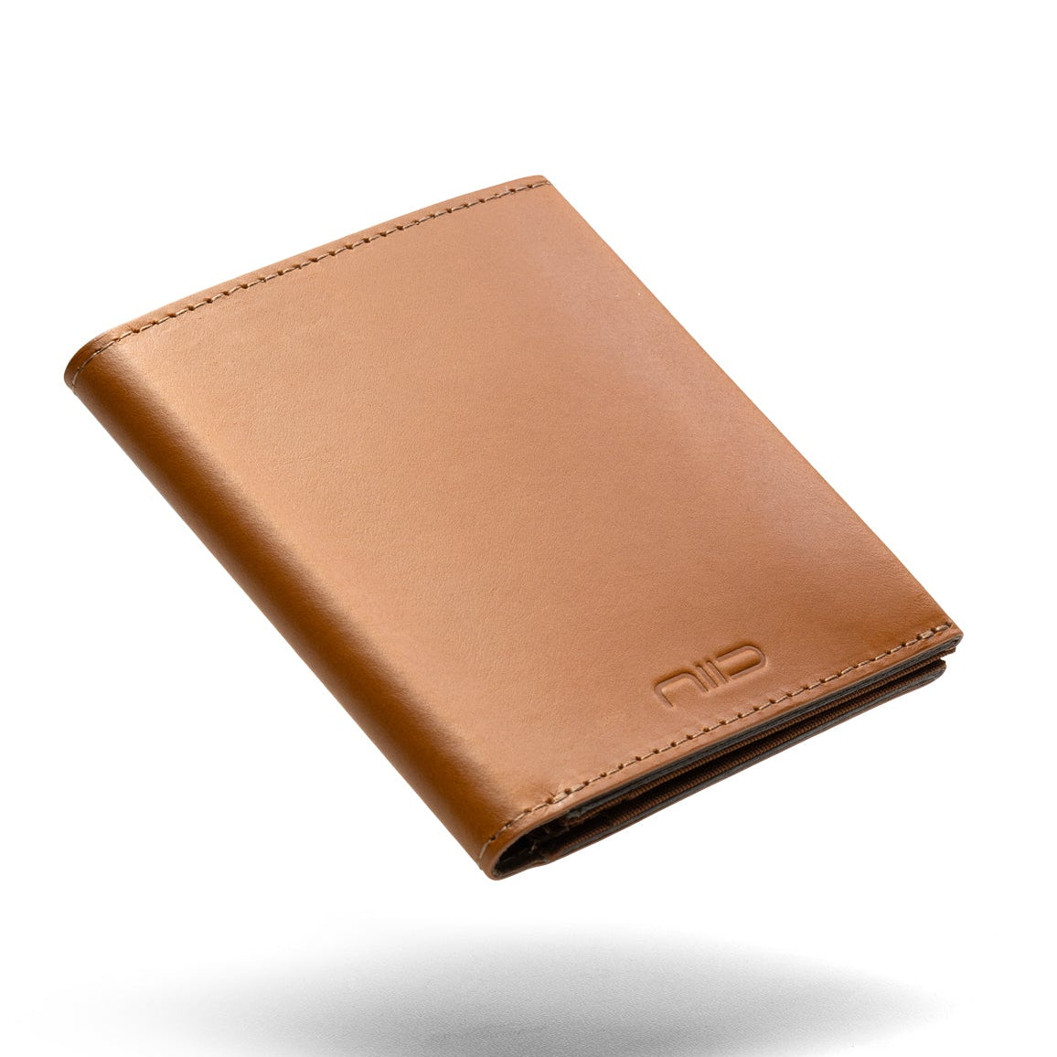 Floating angled shot of tan genuine leather NIID NEX slim bifold wallet on clean solid white background, soft subtle shadow underneath, embossed NIID logo on lower front, smooth vintage leather minimalist men’s front pocket card holder product photography