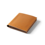 Floating angled shot of tan genuine leather NIID NEX slim bifold wallet on clean solid white background, soft subtle shadow underneath, embossed NIID logo on lower front, smooth vintage leather minimalist men’s front pocket card holder product photography
