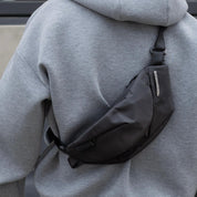 Real‑customer lifestyle shot of NIID Radiant R2 modular everyday sling bag in Diamond Grid Black, worn cross‑back over casual heather grey hoodie. Highlights matte textured fabric, metallic brand badge and fully adjustable strap for daily urban EDC carry.