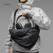 NIID Radiant R2 Everyday Sling Bag Gray Shadow Grid modular crossbody sling bag, man carrying bag with over‑ear headphones inside, urban EDC tech sling