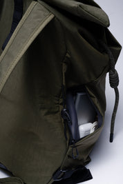 Close-up detail shot of olive green NIID VIA roll-top backpack, featuring secure side zipper pocket that holds chargers and small daily tech gadgets for easy quick access