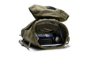 Open olive green NIID VIA roll-top backpack showing roomy inner compartment, fully packed with books, tablet and headphones to demonstrate generous daily storage space