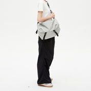 Model carrying NIID VIA Gym‑Bag light‑grey crossbody tote bag, clean white studio backdrop