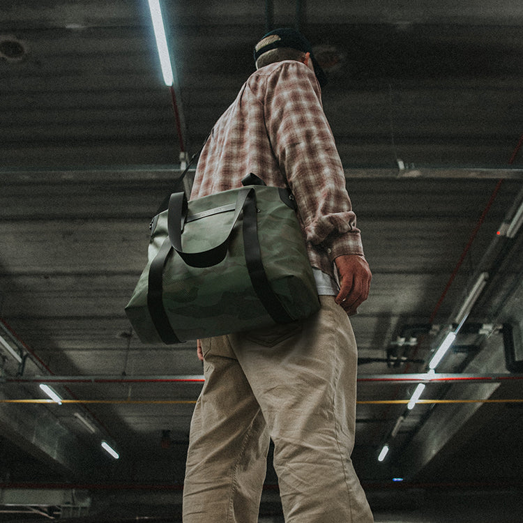 Model carrying the NIID Camo Green Neo Tote on her shoulder, highlighting the bag's versatile size and trendy camo green color in a casual outfit.