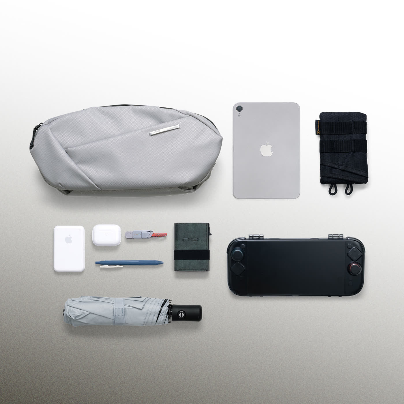 NIID N1L modular sling bag in Pearly Gray shown with everyday carry essentials, including tablet, game console, and accessories, demonstrating excellent organizational capacity.